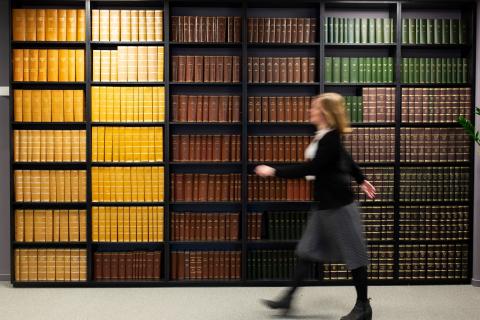 Kvinne går foran bokhylle.